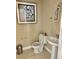Cozy powder room featuring pedestal sink, decorative artwork, and neutral color palette at 7112 Enchanted Lake Dr, Winter Garden, FL 34787