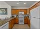 Galley kitchen featuring granite counters, wood cabinets, and modern white appliances at 7512 Seven Eagles Way # 7512, Reunion, FL 34747