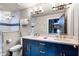Modern bathroom featuring a double vanity with a blue cabinet, shower with glass door, and neutral-toned walls at 1148 Grand Traverse Pkwy, Reunion, FL 34747