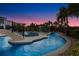 Beautiful pool with waterfall feature, lounge chairs, and lush landscaping at twilight at 1148 Grand Traverse Pkwy, Reunion, FL 34747