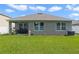 Beautiful backyard with a well-manicured lawn, gray house, and cozy covered patio at 1150 August Sky Dr, Deltona, FL 32738