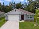 Charming single-story home with a two-car garage, manicured lawn, and mature trees, creating an inviting curb appeal at 1150 August Sky Dr, Deltona, FL 32738