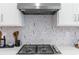 Modern kitchen featuring a cooktop with a stylish backsplash and stainless steel range hood at 1224 Teal Creek Dr, St Cloud, FL 34771