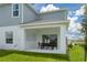 View of back of home with covered patio, outdoor table and chairs, grassy area, and cloudy skies above at 1234 Sand Torch Cir, Davenport, FL 33837