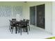 A patio with an outdoor dining table and chairs beside sliding glass doors and decor on the wall at 1234 Sand Torch Cir, Davenport, FL 33837