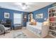 Stylish blue bedroom with a daybed, bookshelves, and a ceiling fan at 12862 Strode Ln, Windermere, FL 34786