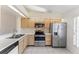 Well-lit kitchen featuring stainless steel appliances, light wood cabinets and tile floors at 13852 Timberbrooke Dr # 203, Orlando, FL 32824