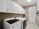 Laundry room with white cabinets, neutral walls, utility sink, and front loading washer and dryer at 14172 Hutchinson St, Winter Garden, FL 34787