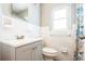 Bright bathroom featuring a sink vanity, white tiled walls, toilet, window, and a patterned shower curtain at 1607 India Palm Dr, Edgewater, FL 32132