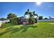 Large grassy backyard featuring a screened lanai surrounded by palm trees and landscaping at 222 Via Mariel E Dr, Davenport, FL 33896