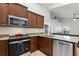 Kitchen featuring stainless steel appliances, granite countertops, and brown cabinets at 222 Via Mariel E Dr, Davenport, FL 33896