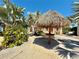 Community area featuring thatched shade umbrellas among sandy walkways, landscaping, and colorful homes at 3095 Key Lime Loop, Kissimmee, FL 34747