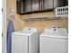Modern laundry room with front loading washer and dryer, overhead storage, and ironing board at 3095 Key Lime Loop, Kissimmee, FL 34747