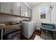 Well-lit laundry room featuring gray cabinets, stainless steel sink, modern washer and dryer, and pet amenities at 3252 Jackson Bluff Way, Clermont, FL 34711