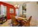Charming dining area with red walls, a wooden table, and a view into the bright, well-lit kitchen at 3621 Casello Dr, New Smyrna Beach, FL 32168