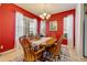 Formal dining room featuring vibrant red walls, elegant chandelier, and natural light from bright windows at 3621 Casello Dr, New Smyrna Beach, FL 32168