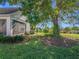 Lush backyard featuring well-maintained lawn, mature tree, and glimpse of surrounding neighborhood at 3635 Kingswood Ct, Clermont, FL 34711