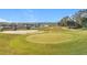 Scenic golf course view featuring a pristine green with sand traps and a lake in the distance at 3635 Kingswood Ct, Clermont, FL 34711