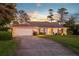 Charming brick home featuring a well-maintained lawn, mature trees, and a long driveway leading to an attached garage at 425 N Pine Meadow Dr, Debary, FL 32713