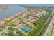 Aerial view of coastal community featuring red roofs, water views, pool and tennis courts at 445 Bouchelle Dr # 104, New Smyrna Beach, FL 32169
