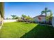 Wide shot of home's backyard featuring green lawn, tropical foliage, and a white vinyl fence at 4862 Grand Vista Ln, St Cloud, FL 34771