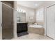 This is a bathroom with granite counters, dark cabinets, a walk-in shower, and separate tub beneath a window with shutters at 4862 Grand Vista Ln, St Cloud, FL 34771
