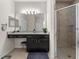 A bathroom featuring granite counters, dark cabinets with drawers, a walk-in shower, and a large mirror with vanity lighting at 4862 Grand Vista Ln, St Cloud, FL 34771