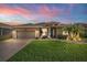 Exterior of home at sunset featuring a spacious lawn, a paver driveway, and a two-car garage at 4862 Grand Vista Ln, St Cloud, FL 34771