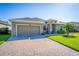 Charming exterior of home with a two-car garage, paver driveway and well-manicured lawn at 4862 Grand Vista Ln, St Cloud, FL 34771