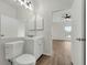 Bright bathroom featuring a white vanity, large mirror, and toilet, plus wood-look flooring extending into the next room at 5669 Parkview Lake Dr, Orlando, FL 32821
