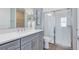 Well-lit bathroom with gray vanity, quartz countertop, and walk-in shower with glass doors at 6006 Forest Perch Dr, St Cloud, FL 34771