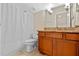 Cozy bathroom features a single sink vanity with granite counters, wood cabinets, and a shower-tub combo at 8706 Irmastone Way, Orlando, FL 32817