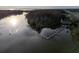 Scenic aerial view of the lake with a wooden dock surrounded by lush greenery at 9560 Starling Loop, Leesburg, FL 34788