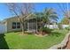 Lush backyard oasis with manicured lawn, tropical palms, and a screened lanai for outdoor enjoyment at 9774 Nonacrest Dr, Orlando, FL 32832
