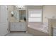 Well-lit bathroom featuring a soaking tub, tiled floors, and a vanity with ample storage space at 9774 Nonacrest Dr, Orlando, FL 32832