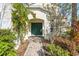 Inviting front entrance with double green doors, a brick path, and beautiful flowering plants at 1207 Winding Cypress Ct, Kissimmee, FL 34746