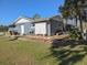 Spacious backyard showcasing the home's exterior, a wooden exterior door, landscaping, and partial shade at 11847 Ocklawaha Dr, Leesburg, FL 34788