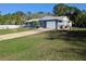 Single-story home with a lush green lawn and mature trees, and a long driveway at 11847 Ocklawaha Dr, Leesburg, FL 34788