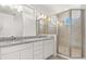 Bright bathroom with double sinks, granite counters, white cabinets, and glass-enclosed shower at 14165 Moniz Ave, Orlando, FL 32827