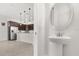 Stylish powder room features a pedestal sink and a round mirror, located near the kitchen at 14165 Moniz Ave, Orlando, FL 32827