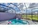 A private, screened in pool is surrounded by green landscaping and a view of the neighborhood at 159 Captiva Dr, Davenport, FL 33896