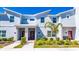 Stylish townhome featuring brick accents, manicured landscaping, and a vibrant red front door, enhanced by a clear blue sky at 2636 Reading Trl, Kissimmee, FL 34746