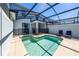 Sparkling private pool enclosed in a screened patio, featuring a grill, seating, and a safety fence at 2636 Reading Trl, Kissimmee, FL 34746