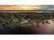Stunning lakefront estate with lush greenery, a private dock, and an inviting pool under a colorful sunset sky at 2844 Marquesas Ct, Windermere, FL 34786