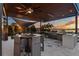 Outdoor kitchen with ceiling fan, built-in grill, bar seating, and beautiful sunset views over the lake at 2844 Marquesas Ct, Windermere, FL 34786