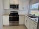 Well-lit kitchen with stainless steel appliances, and white cabinets, overlooking the yard at 373 Caribbean Dr, Davenport, FL 33897