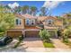 Exterior view of the townhome featuring a three-car garage, a brick driveway, and mature trees at 4952 Matteo Trl, Orlando, FL 32839
