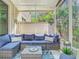 Relaxing screened porch with comfortable blue seating, glass table, and view of the beautiful trees in the backyard at 4952 Matteo Trl, Orlando, FL 32839