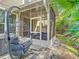Cozy porch with swinging chair and view of the screened porch with comfortable blue seating, glass table, and backyard at 4952 Matteo Trl, Orlando, FL 32839
