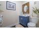 Well-lit half-bathroom featuring a blue vanity, decorative mirror, and charming wall art at 500 Forest Lake Dr, Altamonte Springs, FL 32714